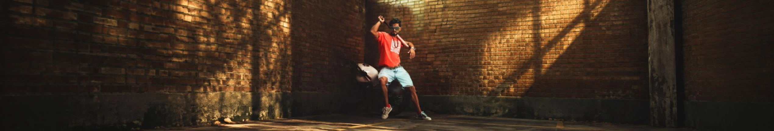 A model in a red T-shirt against a sunlit brick wall for 7&2