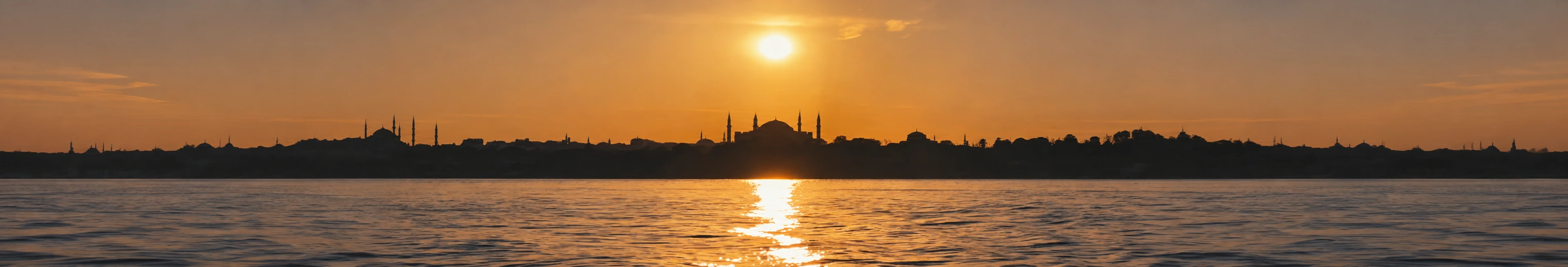 Istanbul skyline silhouetted against a golden sunset over the water