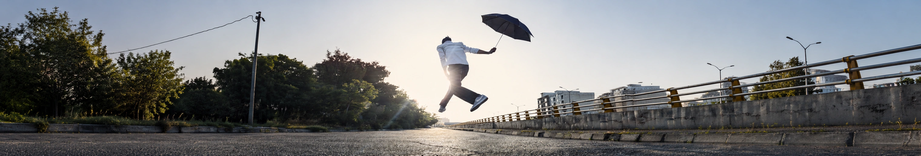 A man suspended above a road holding a black umbrella in Mamal Air