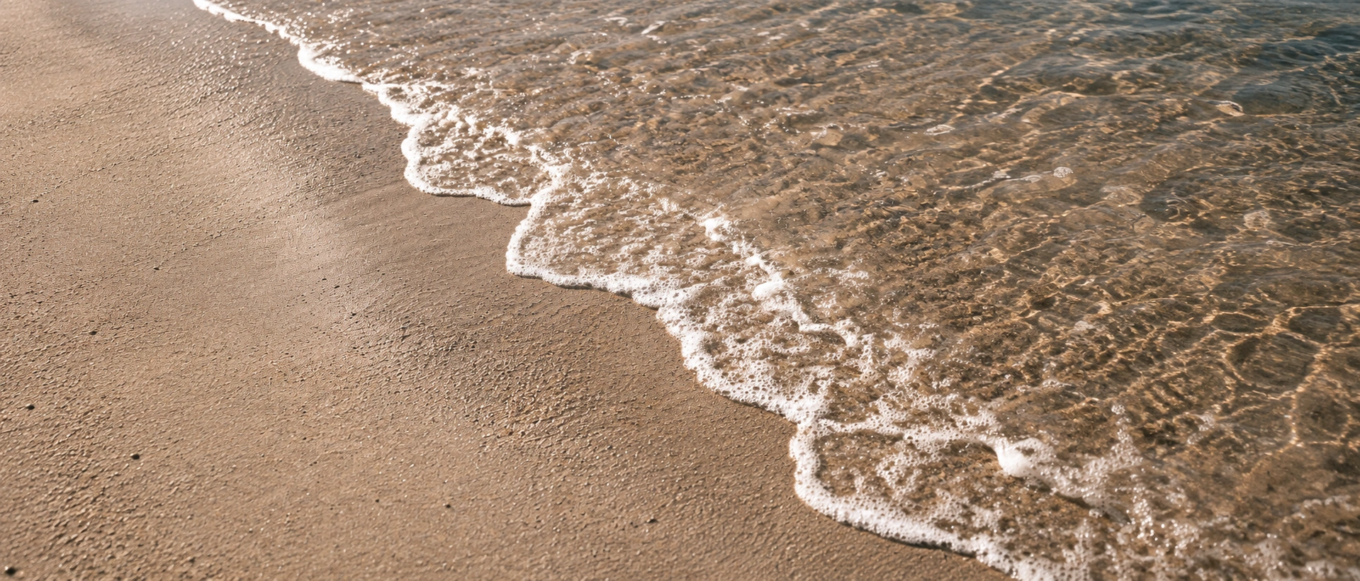 Gentle waves washing over a sunlit sandy shoreline