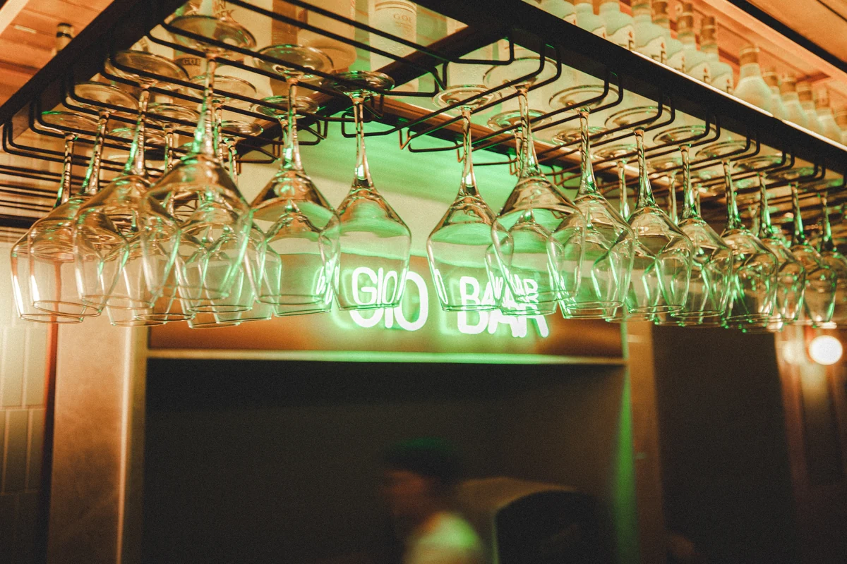 Hanging glassware illuminated by a green bar sign
