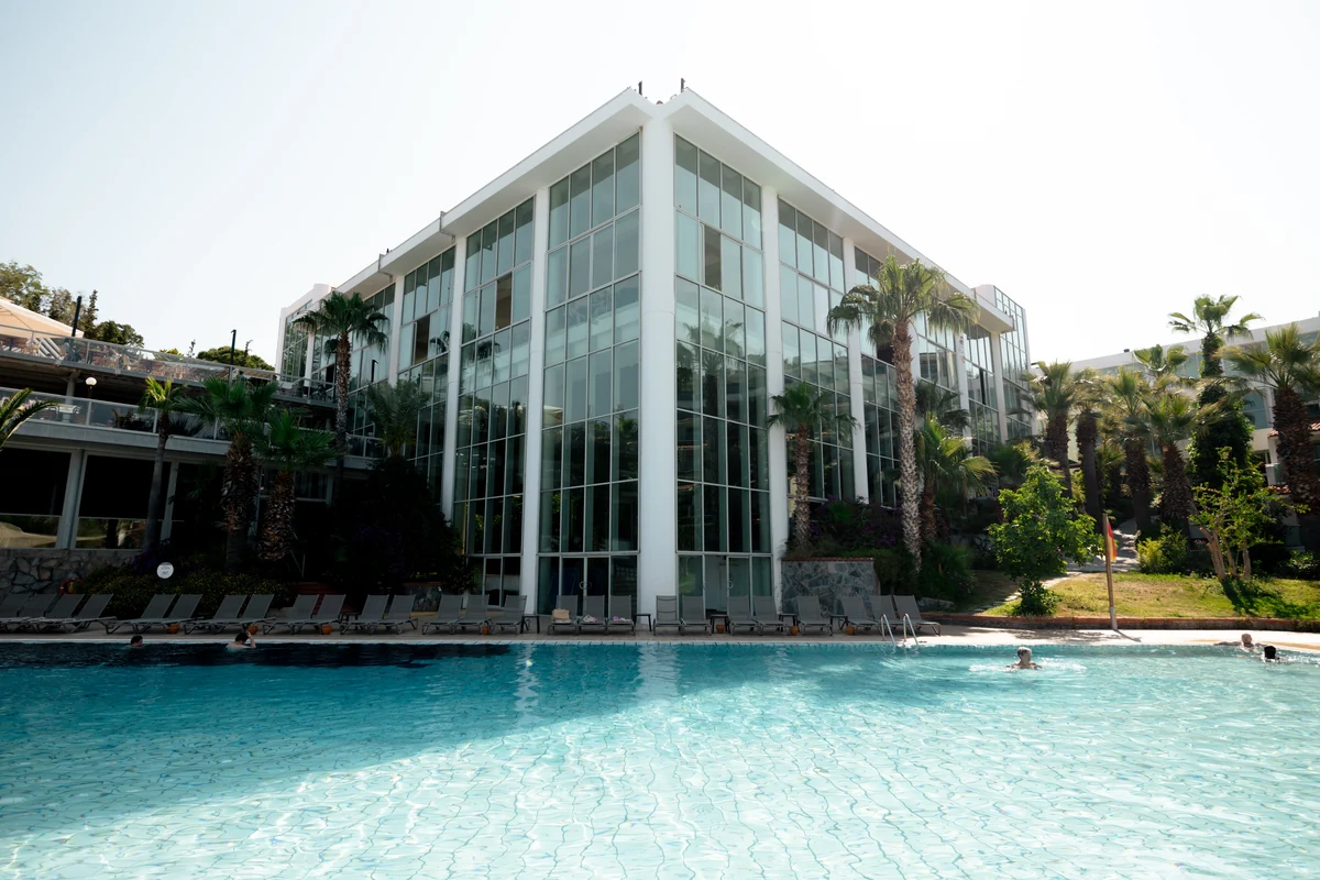 A glass-fronted building and palm trees beside a swimming pool